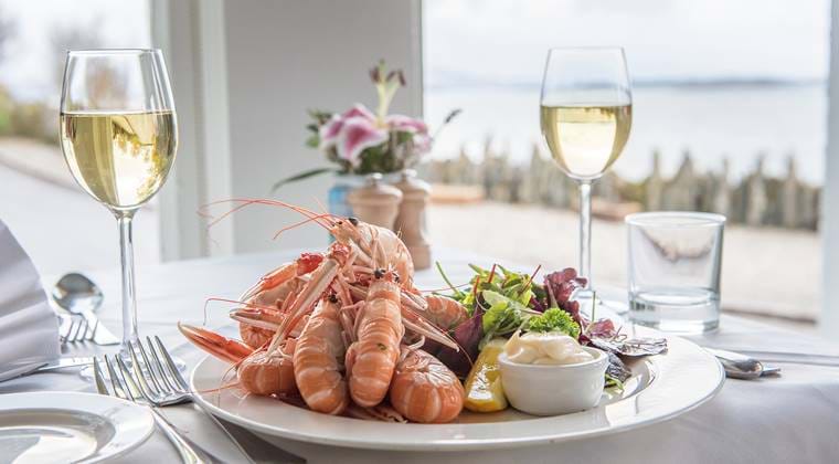 Plate of langoustines and glasses of white wine.