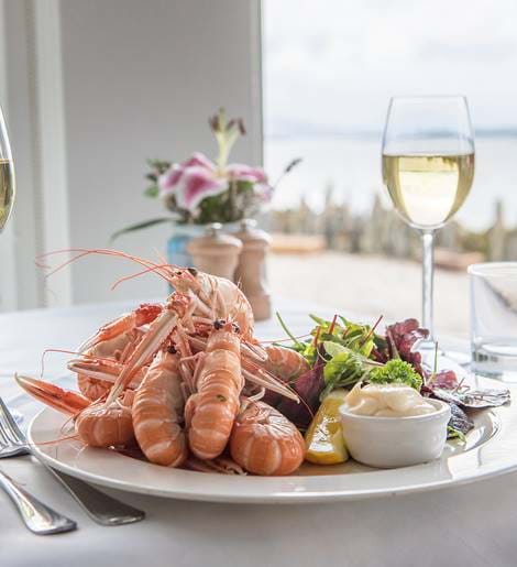 Plate of langoustines and glasses of white wine served at Crinan Hotel.