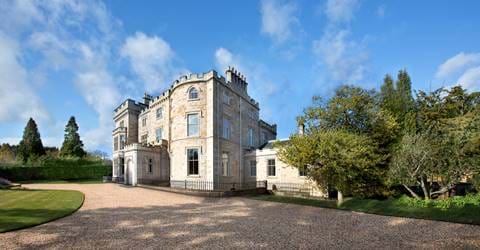 Exterior of Crossbasket Castle Hotel in Scotland with a clear blue sky.