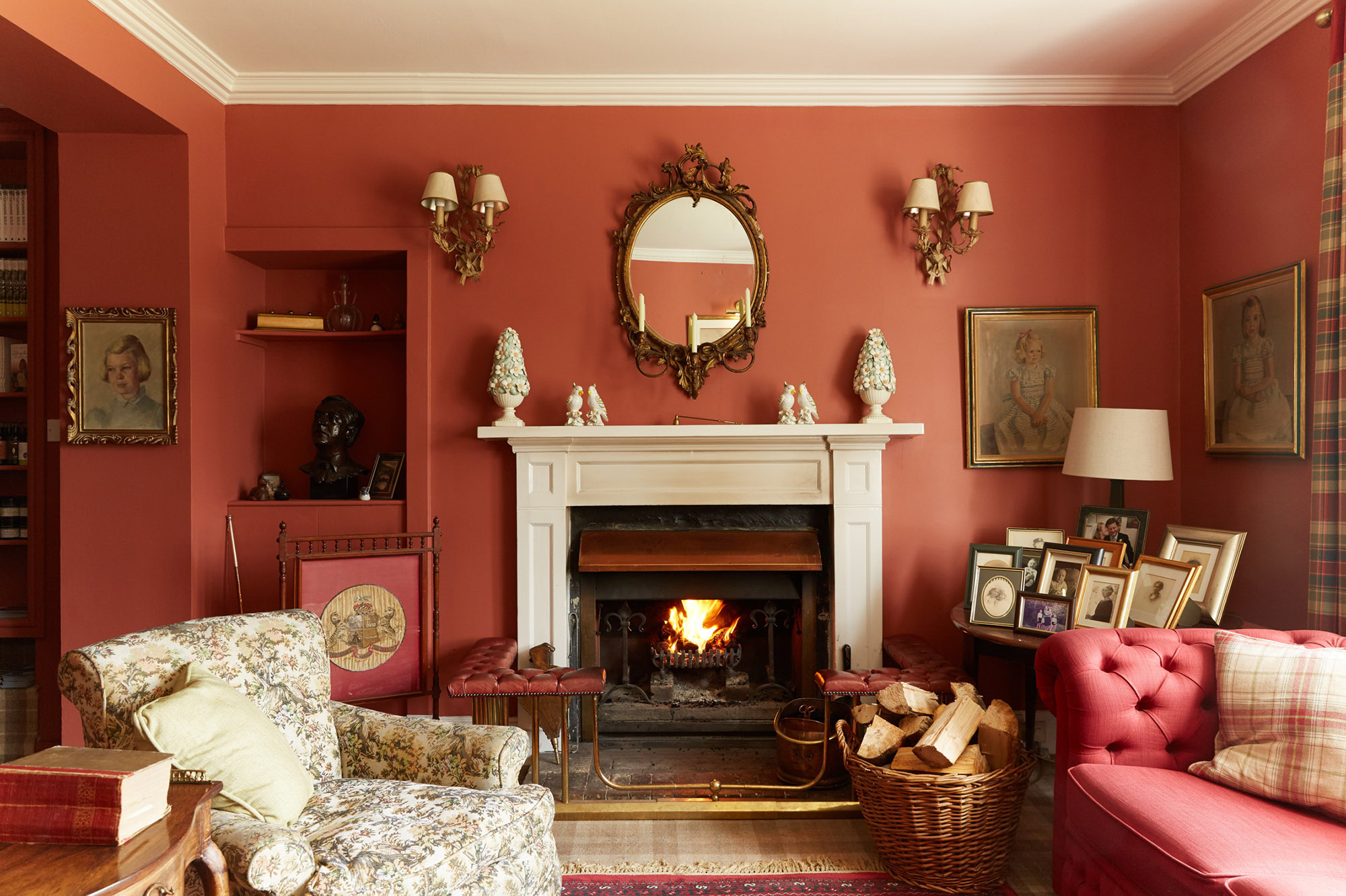 A cosy living room with a fireplace, red walls, and vintage decorations at Kinloch Lodge in Scotland.