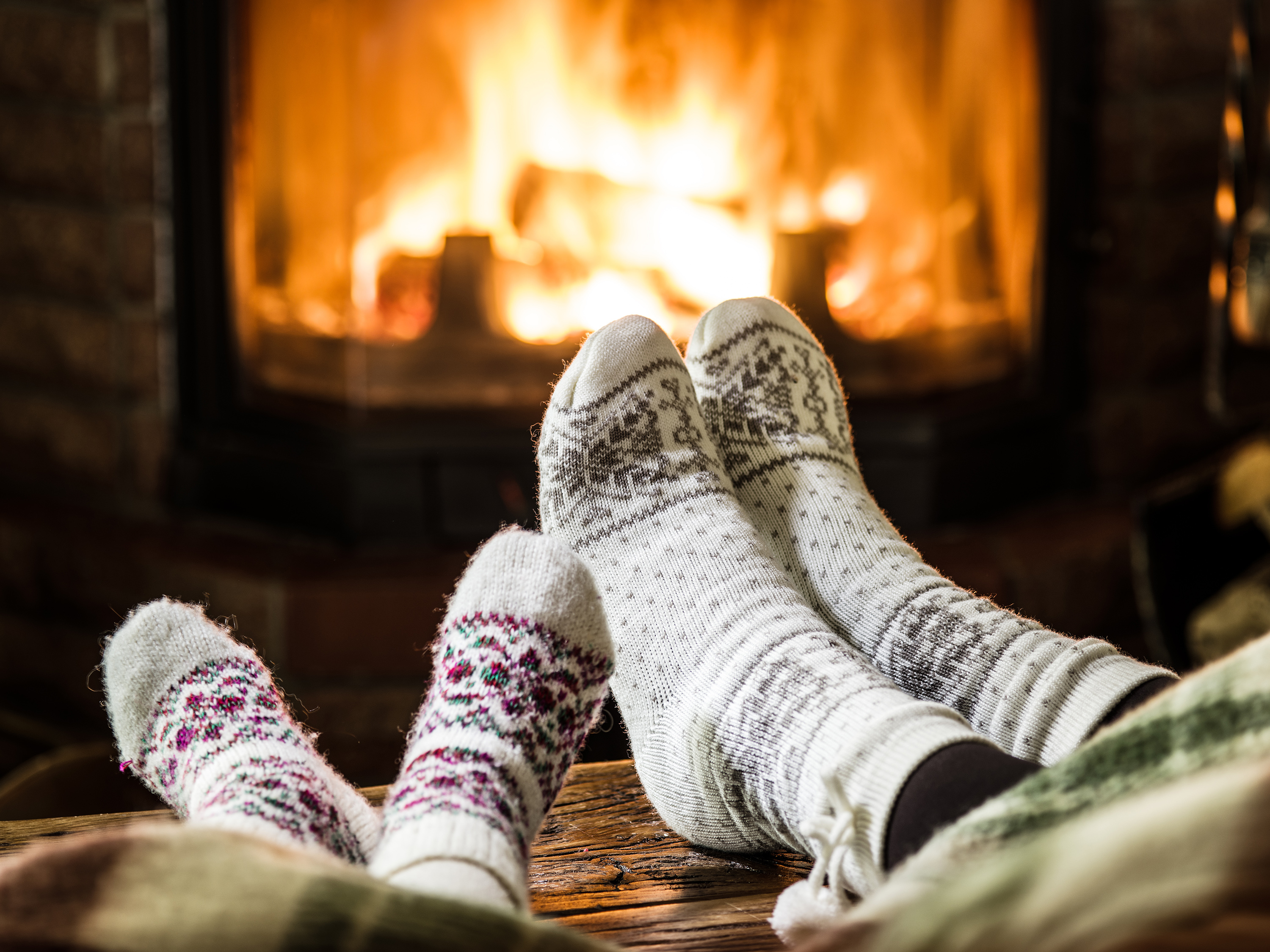 Two people wearing wooly socks in front of a fire
