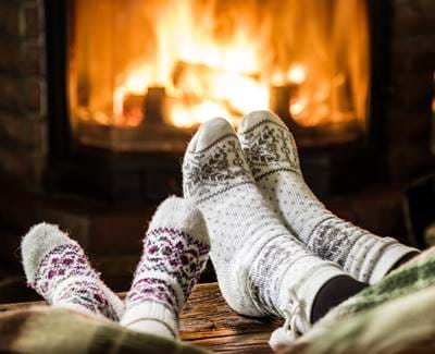 Two people wearing wooly socks in front of a fire