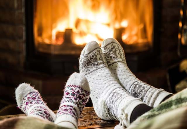 Two people wearing wooly socks in front of a fire