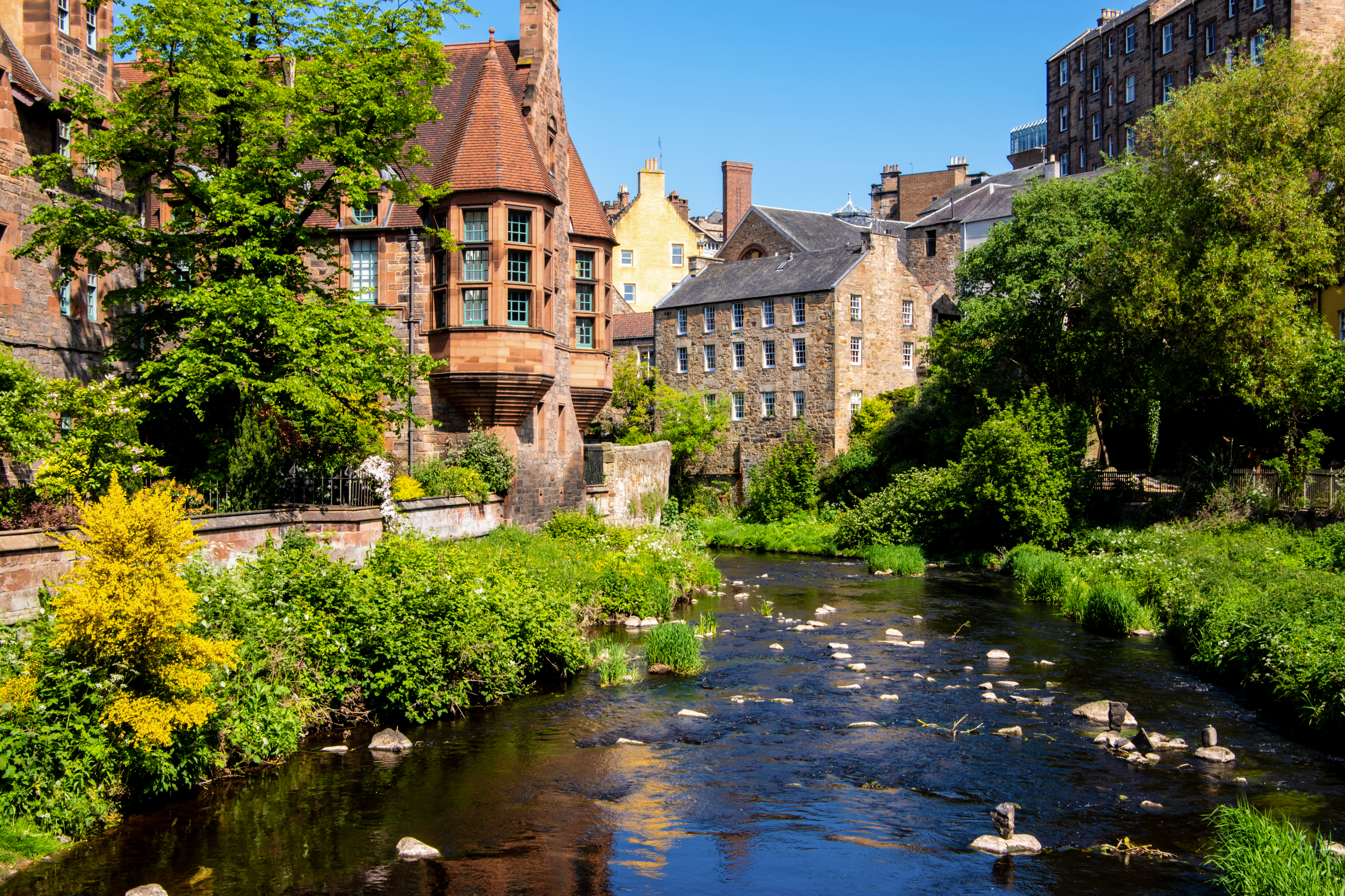 Dean Village in Edinburgh with lush green trees, along the peaceful river of Leith.