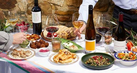 A table set with an array of food dishes, wine, and glasses, ready for a meal.